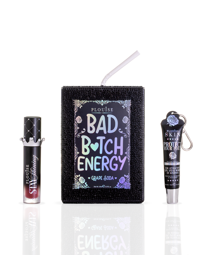 A black gemstoned P.Louise juice box featuring a straw and a large holographic label reading 'BAD BITCH ENERGY Grape Soda' flanked by a black lip oil tube on the left and a black lip conditioner tube on the right, all on a white background with a reflection below.