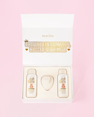An image of an opened P.Louise Hair To The Throne coconut cake haircare set against a pink background