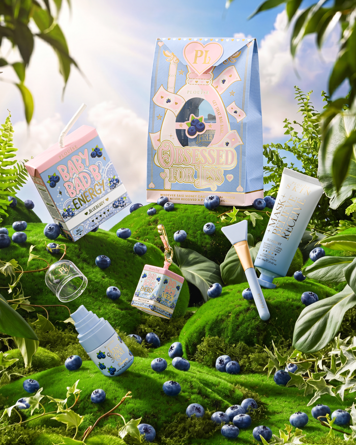 P.Louise Obsessed For Bad Bitch Blueberry full skincare and lipcare bundle on a grassy hill surrounded by blueberries