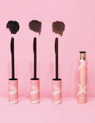 3 P.Louise Tearproof waterproof mascara wands with their color swatch next to each one and the pink product tube on the end against a pink background