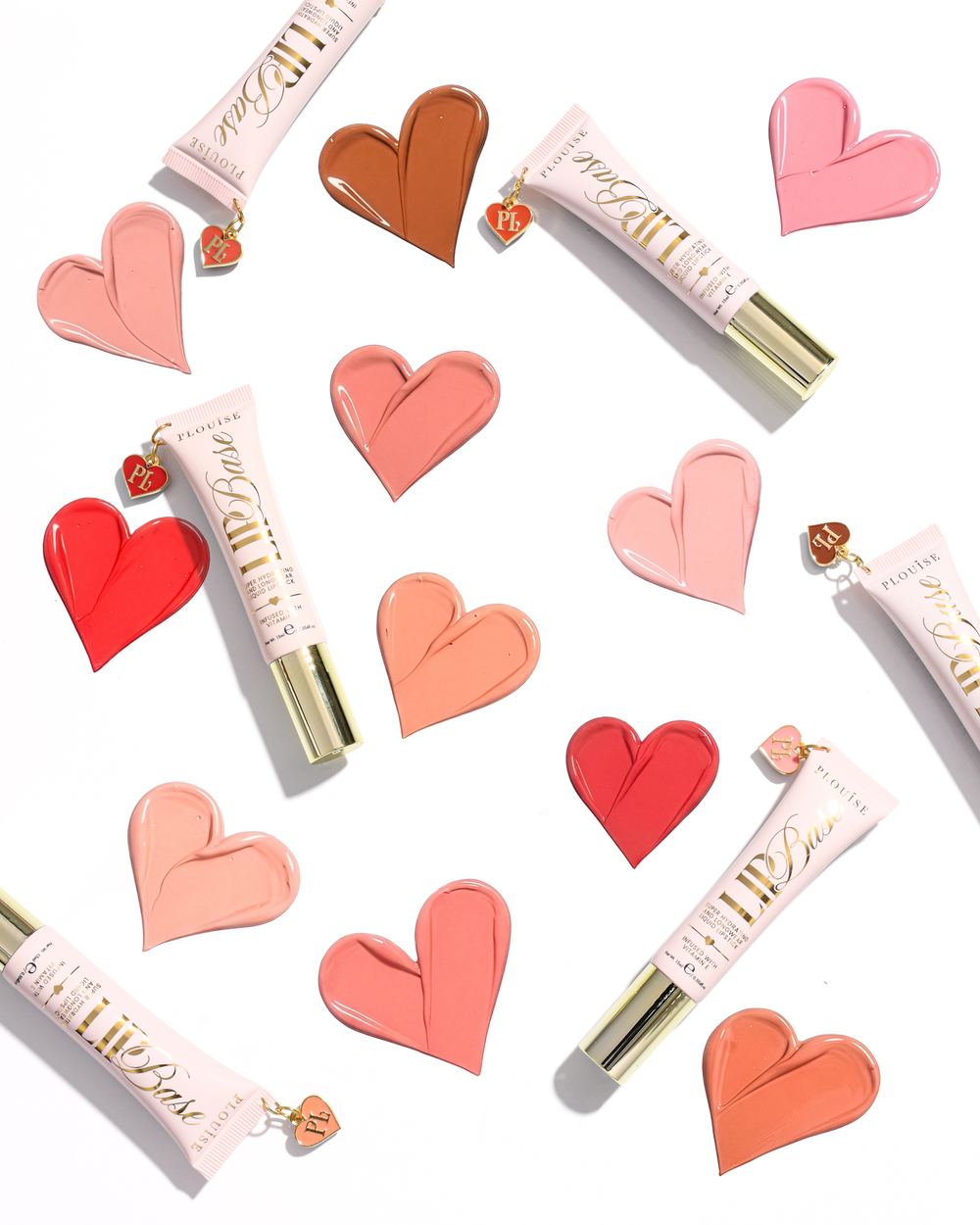 Several tubes of P.Louise Lip Base in shades of pink, coral, and peach, arranged on a white background with matching heart-shaped lip swatches and small love charms.